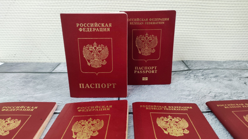 Два загранпаспорта РФ на фоне светлой стены и плитки