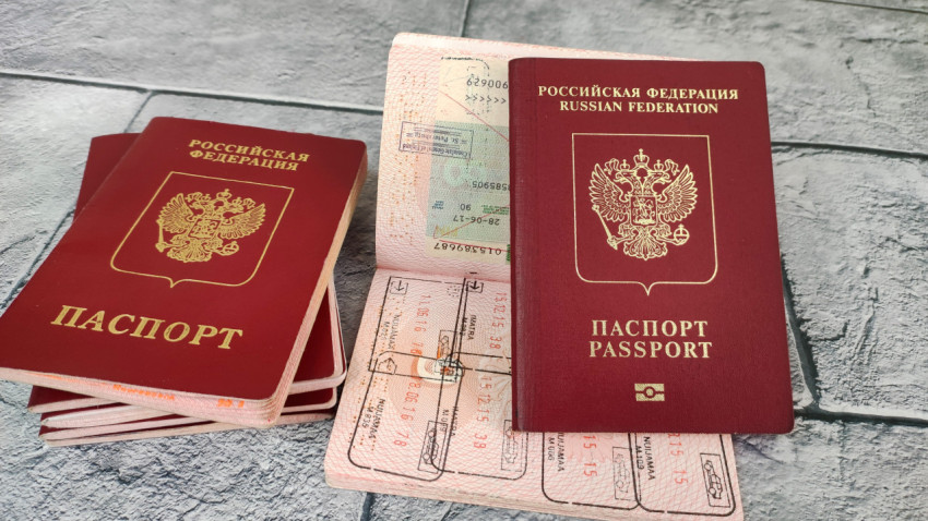 Биометрический загранпаспорт РФ вертикально на фоне визовых страниц