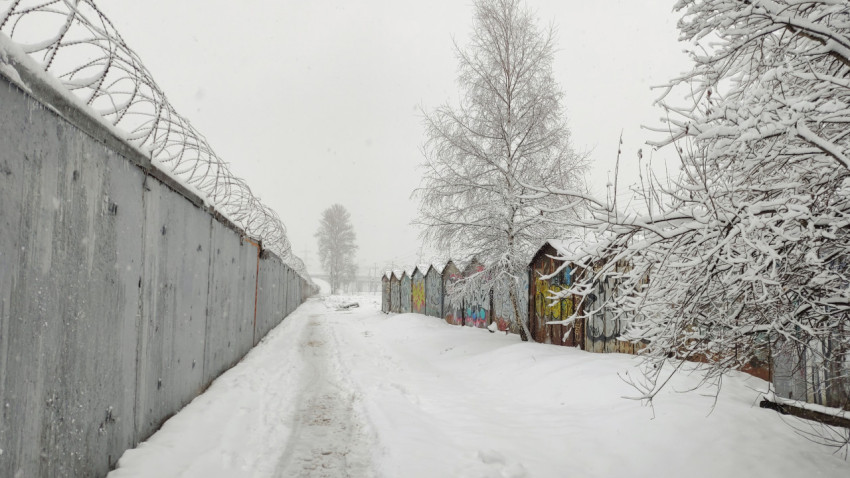 Проход вдоль бетонного забора и гаражей зимой