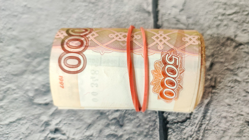 Скрученные купюры в 5000 рублей на фоне плитки