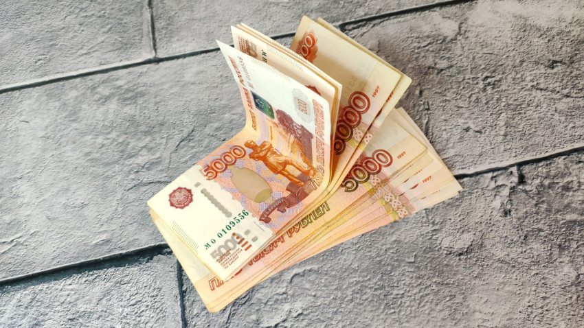 Крупный план стопки купюр по 5000 рублей на каменном фоне