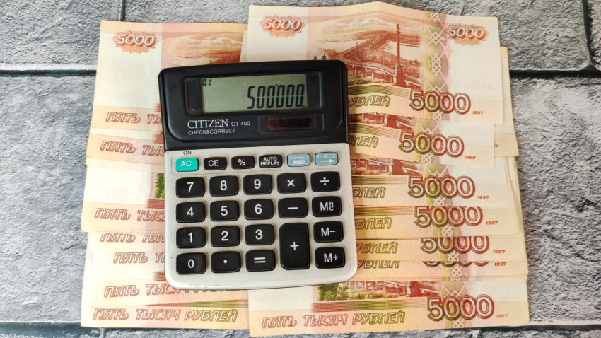 Банкноты 5000 рублей и калькулятор с суммой 500000