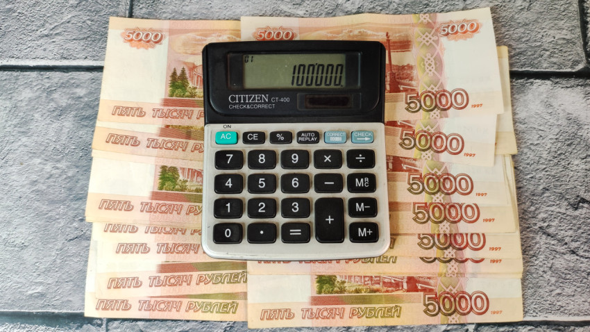 Калькулятор и купюры 5000 рублей с суммой 100000