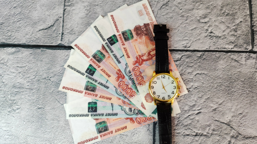 Купюры 5000 и 1000 рублей веером и наручные часы на плитке