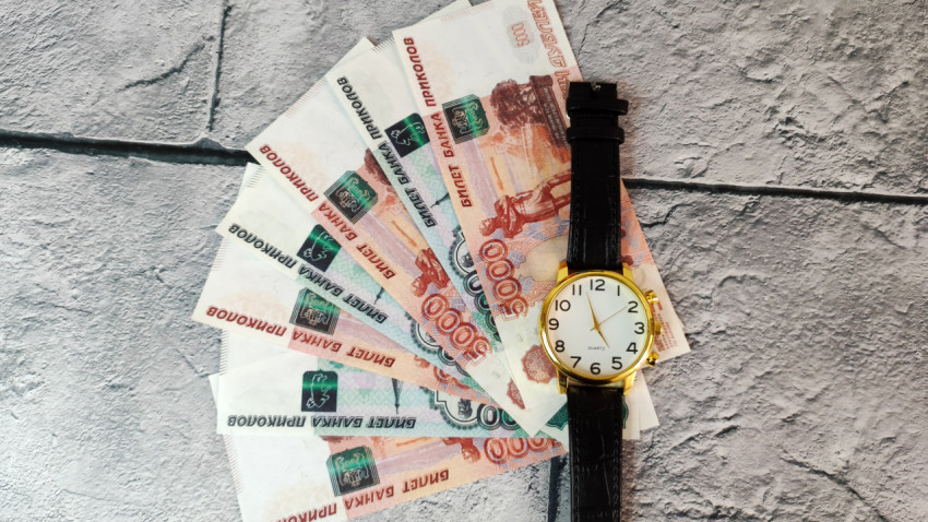 Наручные часы поверх веера из купюр 5000 и 1000 рублей