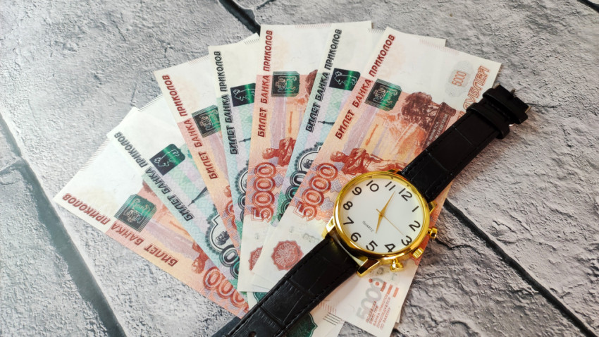 Купюры 5000 и 1000 рублей и часы с золотистым корпусом