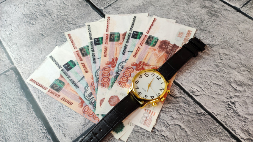 Наручные часы и купюры 5000 и 1000 рублей на плитке