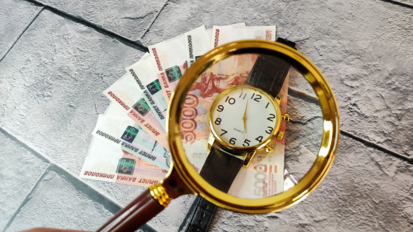 Наручные часы на купюрах 5000 и 1000 рублей под лупой
