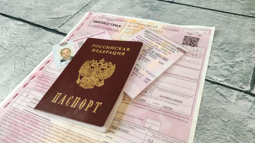Комплект документов для автомобиля на фоне страхового полиса