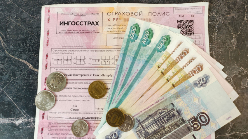 Российский страховой полис ОСАГО и купюры на мраморной поверхности