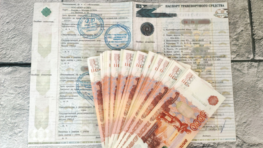 ПТС с разложенными купюрами по 5000 рублей на сером фоне