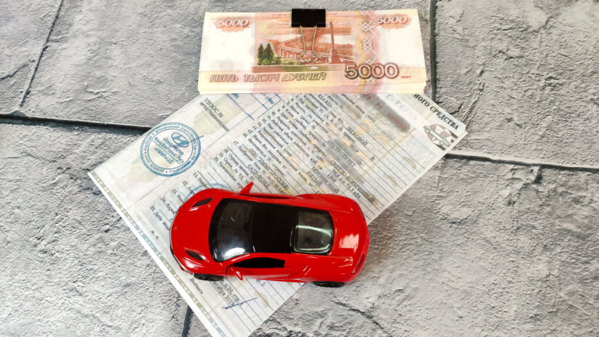 ПТС, купюры и красный игрушечный автомобиль на сером фоне