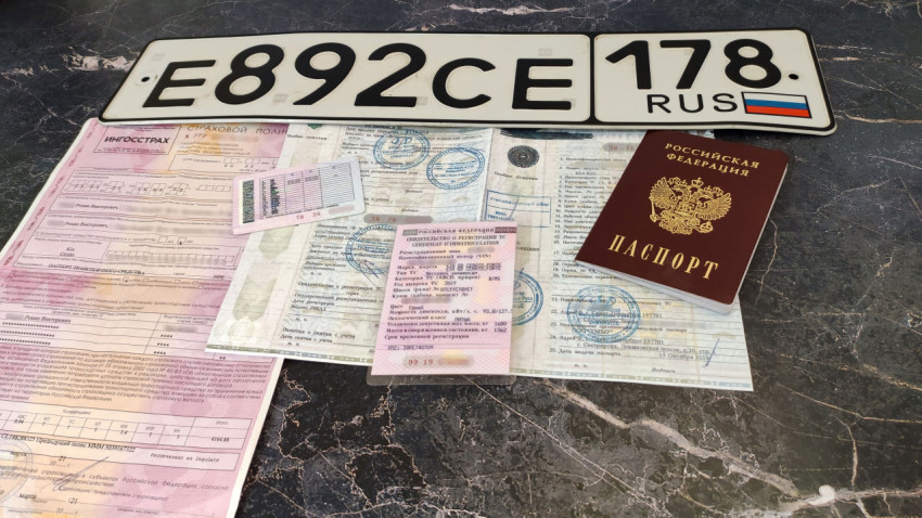 Номерной знак и автодокументы на тёмной мраморной поверхности