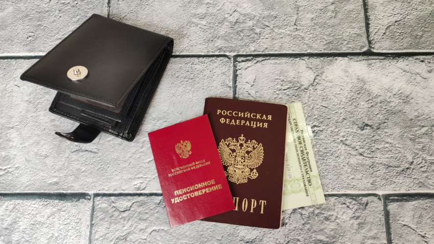 Паспорт, пенсионное удостоверение и СНИЛС рядом с портмоне на сером фоне