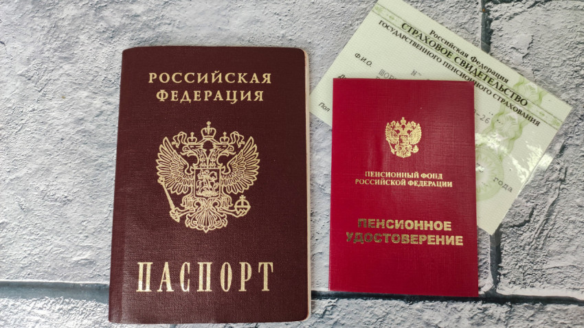 Паспорт, пенсионное удостоверение и СНИЛС на сером фоне