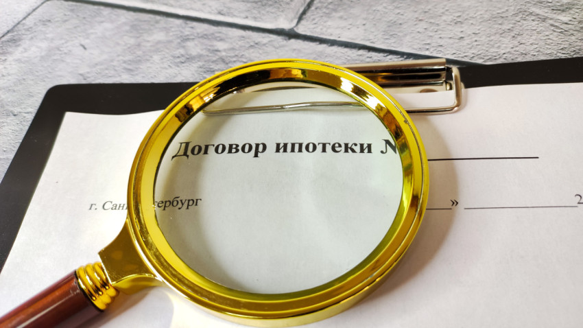 Текст ипотечного договора в фокусе лупы на офисной поверхности