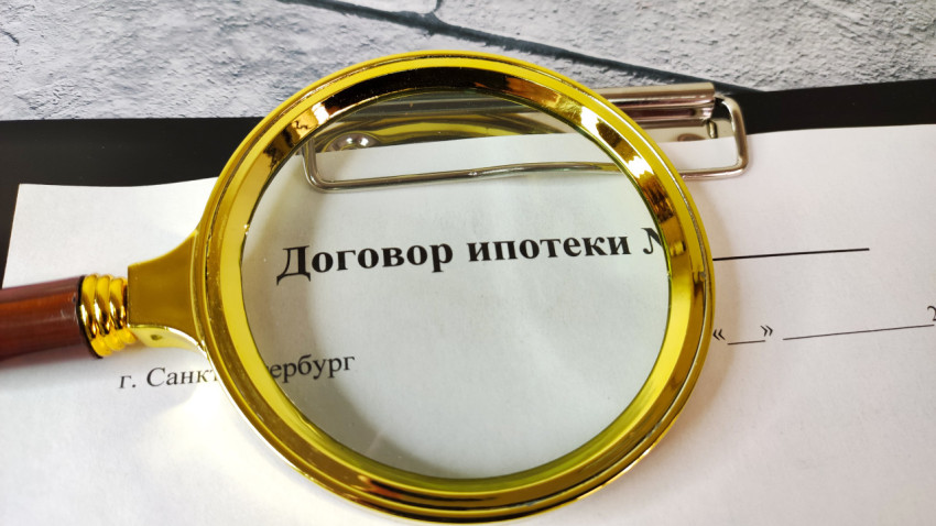 Договор ипотеки под увеличительным стеклом на серой плитке