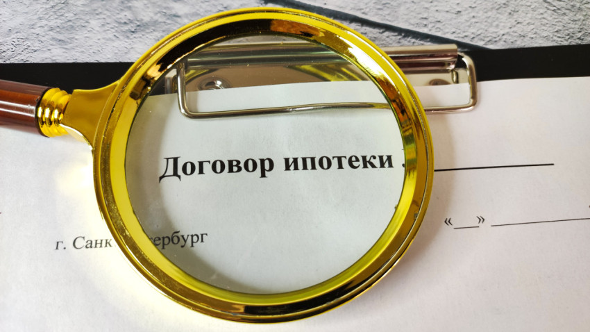 Фрагмент договора ипотеки под лупой на фоне плитки