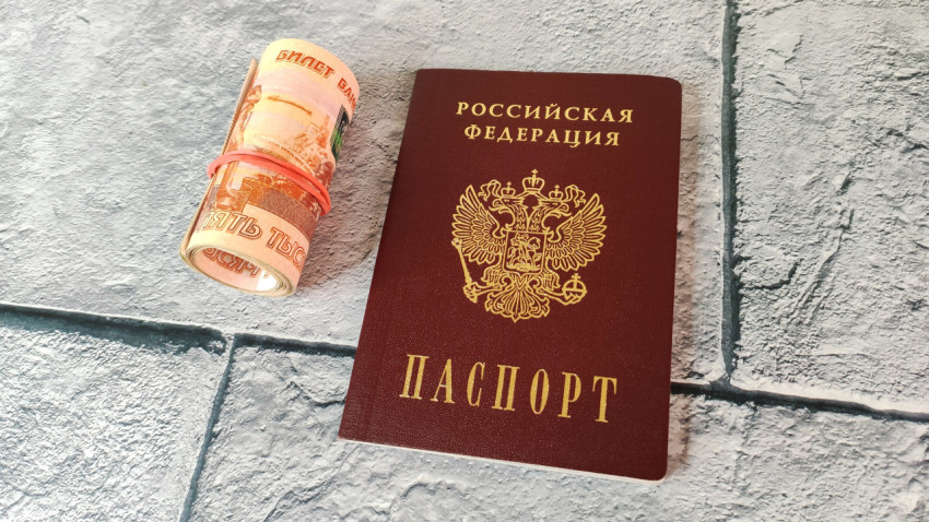 Скрученная купюра и российский паспорт на фоне плитки