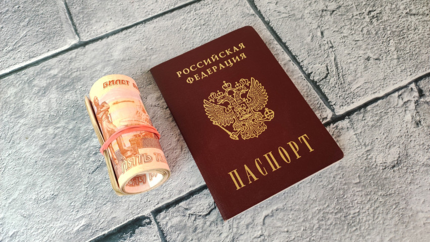 Скрученные пятитысячные купюры и паспорт РФ