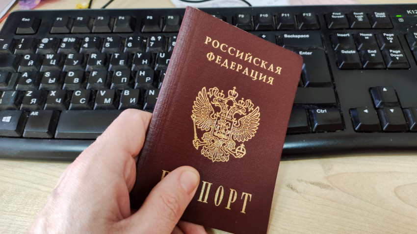 Паспорт гражданина РФ в руке на фоне клавиатуры