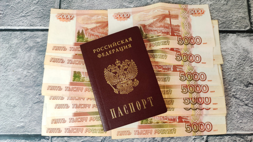 Российский паспорт на фоне пятитысячных купюр