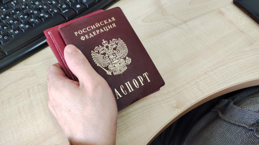Человек держит несколько российских паспортов в руке
