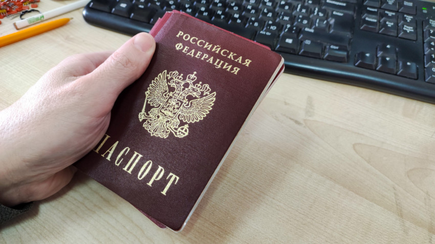 Российский паспорт в руке на рабочем столе с клавиатурой