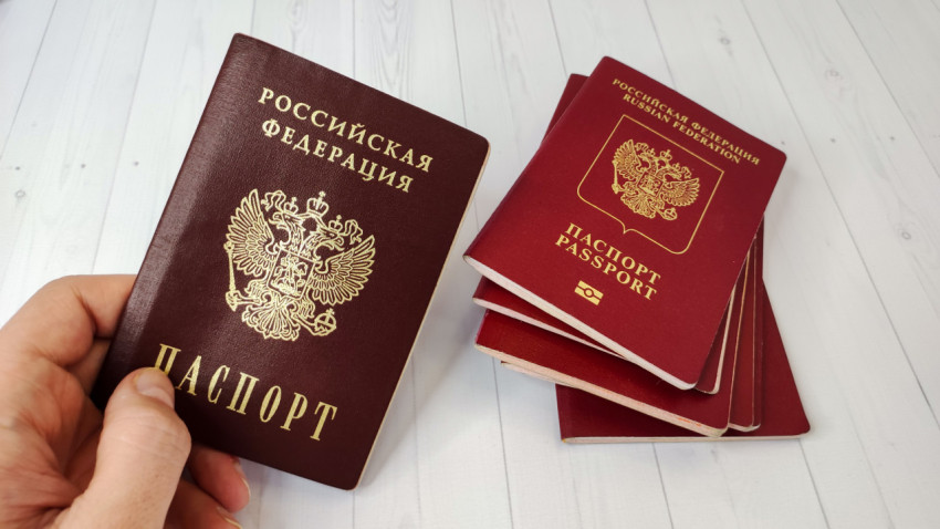 Российский паспорт в руке на фоне заграничных паспортов