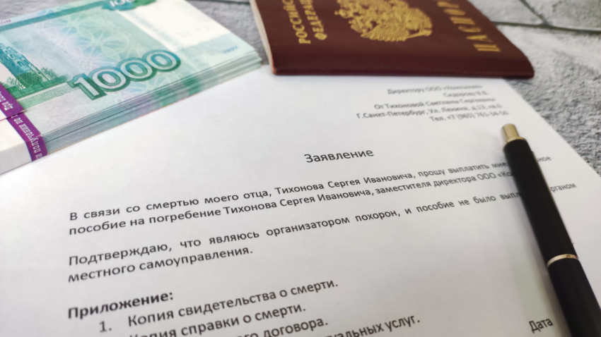 Пачка купюр и заявление о выплате пособия на фоне паспорта