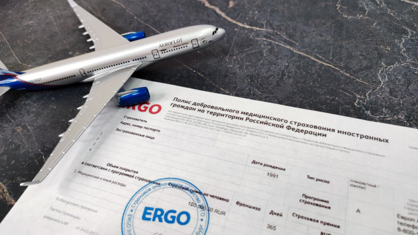 Модель самолета и страховой полис ERGO на столе