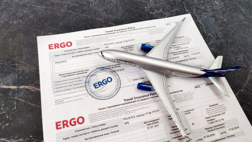 Модель самолета Aeroflot и полис ERGO на фоне страховых документов