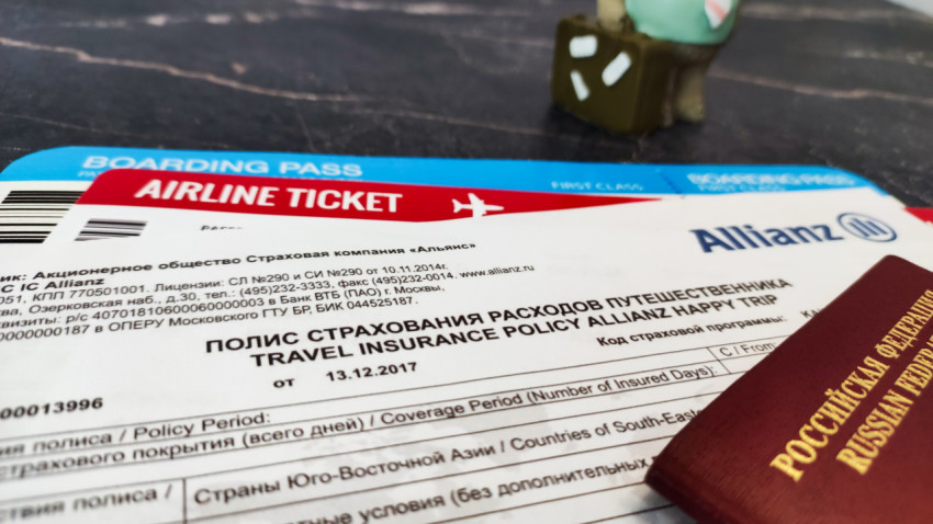 Страховой полис Allianz с авиабилетом и загранпаспортом на столе
