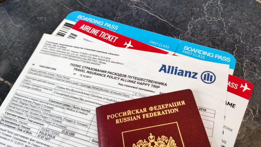 Полис Allianz с авиабилетами и паспортом на тёмном мраморе