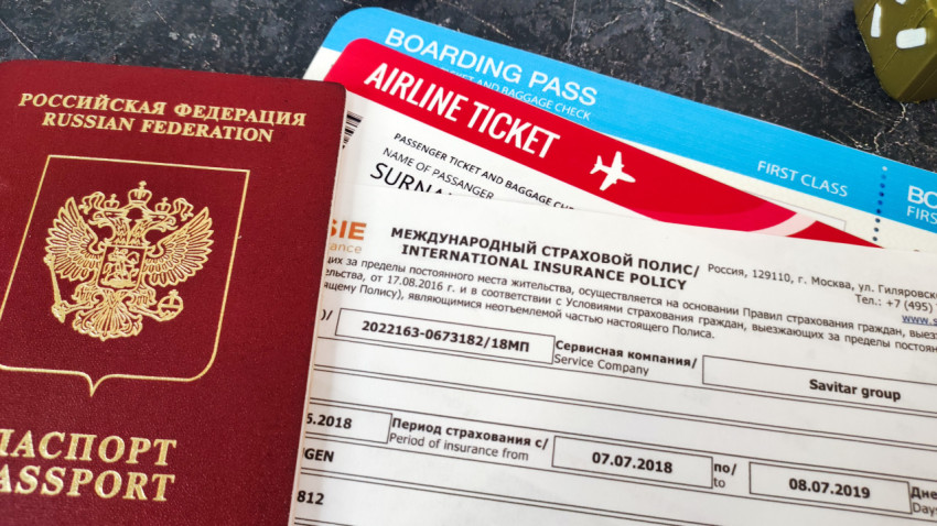 Паспорт и международный страховой полис рядом с билетом на самолёт