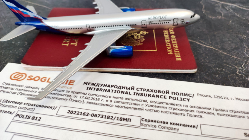 Самолет на фоне загранпаспорта и международного страхового полиса