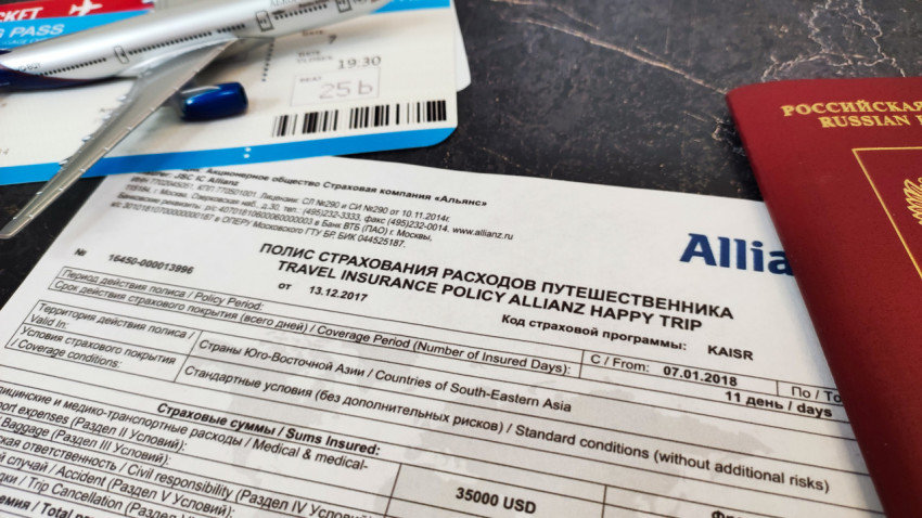 Полис Allianz и паспорт рядом с моделью самолёта