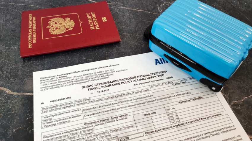 Паспорт и чемодан на фоне полиса Allianz Happy Trip
