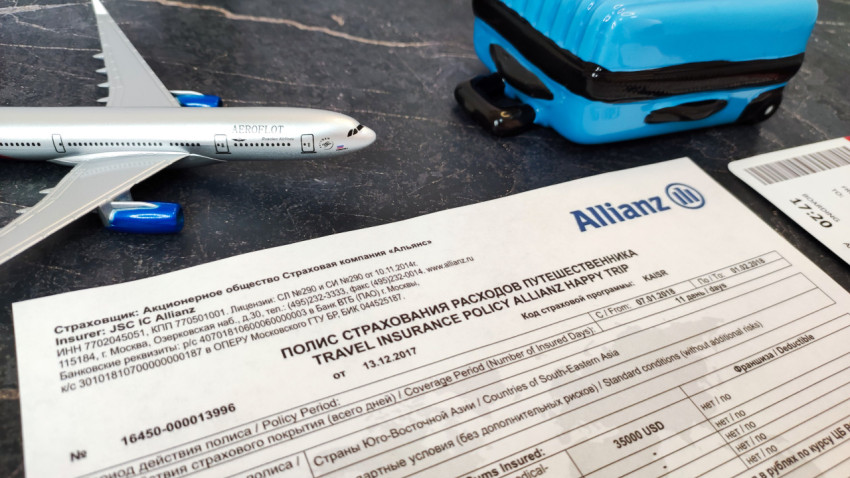 Миниатюрный чемодан и самолёт рядом со страховым полисом Allianz