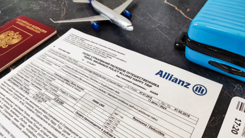 Документы и игрушечный багаж на фоне полиса Allianz Happy Trip