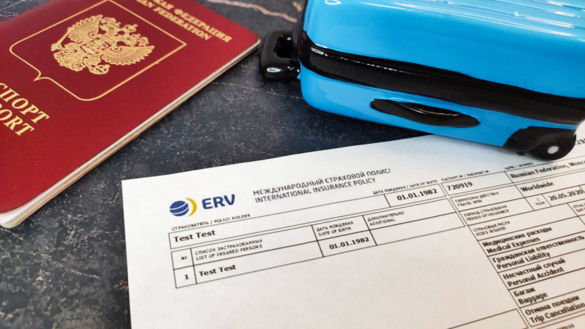 Полис ERV, паспорт РФ и миниатюрный чемодан на столе