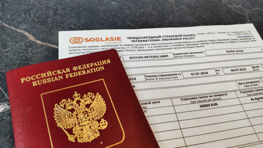 Полис Согласие и заграничный паспорт на тёмной поверхности