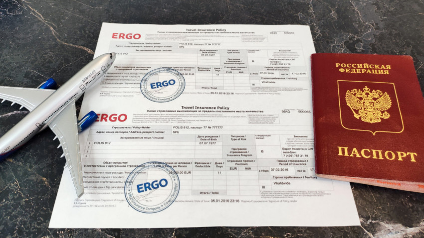 Модель самолета, страховой полис ERGO и загранпаспорт на мраморе