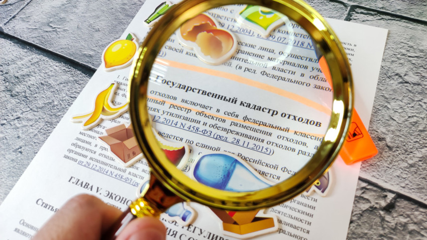 Лупа над статьёй об отходах с наклейками мусора