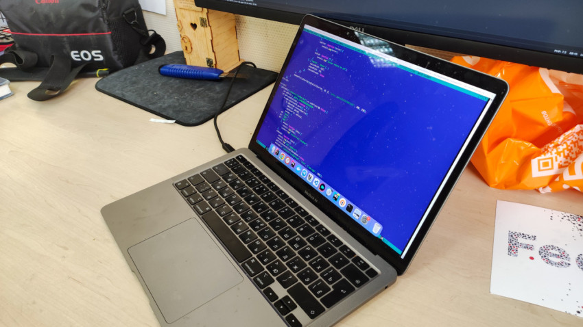 Открытый ноутбук MacBook Air с кодом на экране на офисном столе
