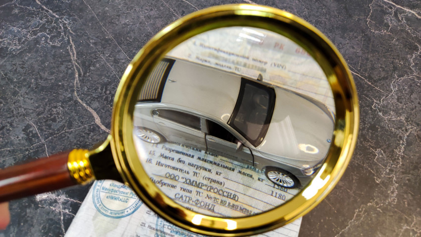 Серебристая модель автомобиля через увеличительное стекло