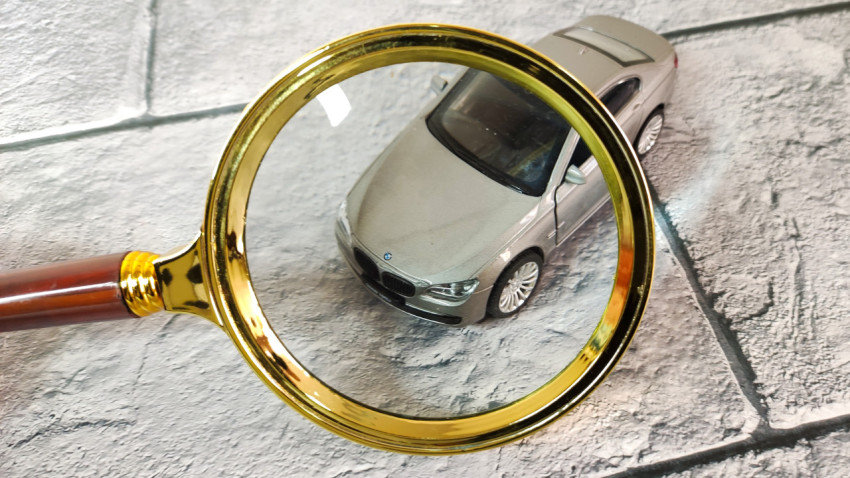 Модель BMW под увеличительным стеклом на фоне плитки