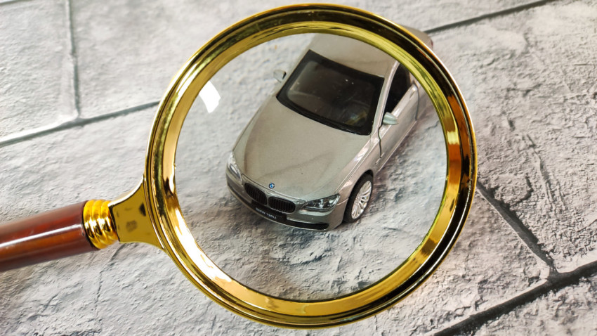 Крупный план игрушечной машины BMW под увеличительным стеклом
