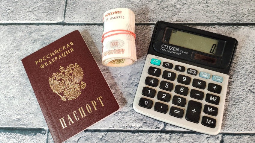 Паспорт, калькулятор и свёрток купюр на фоне плитки
