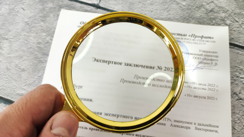 Экспертное заключение в руке под увеличительным стеклом на светлом фоне